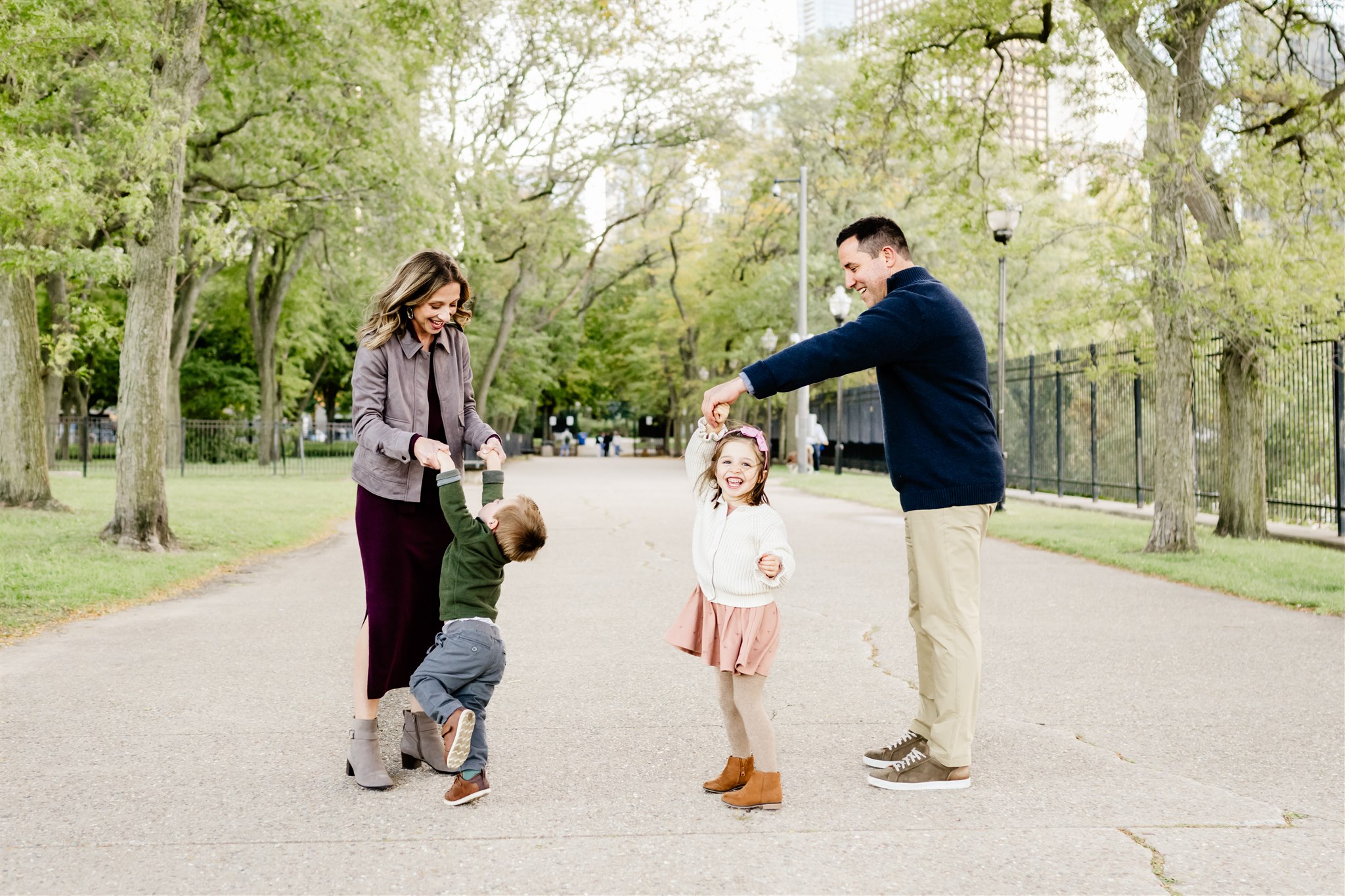 A mom and dad dance and play with their toddler son and daughter in a Best Chicago Neighborhoods for Families park