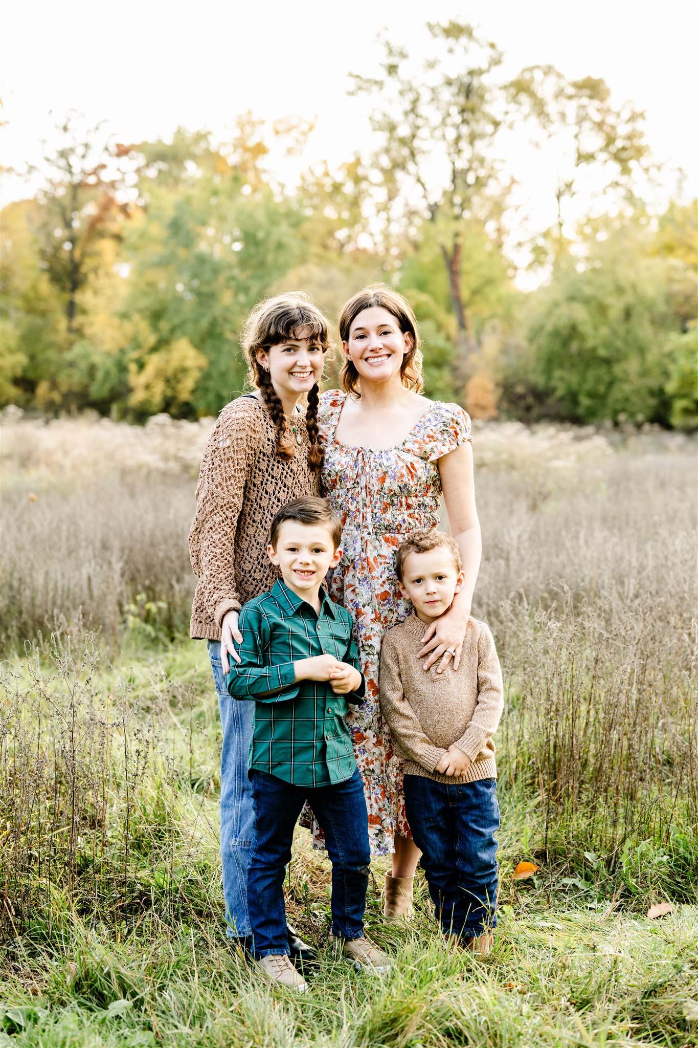 A family of four stand in a park path of tall grass at sunset in one of the Best suburbs of Chicago for families