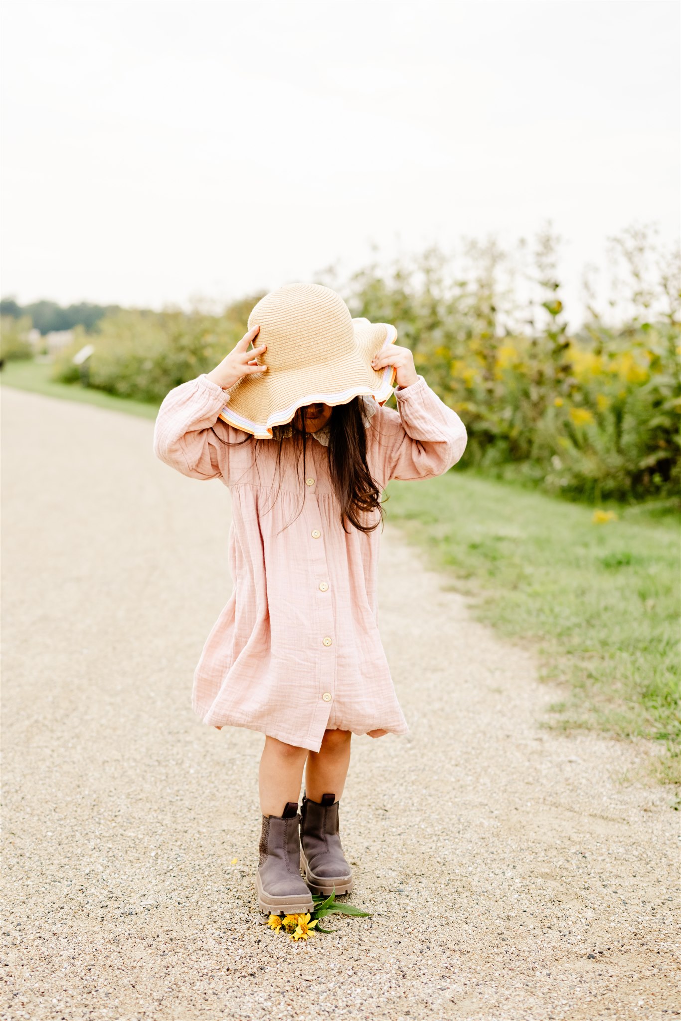 A young girl walks through a park in a pink dress and large sun hat before visiting Dance Academy Chicago