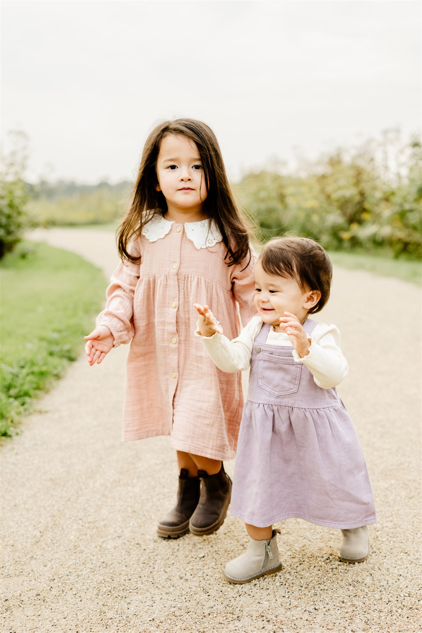 Two toddler girls in dresses walk through a park path before visiting Famous Churches in Chicago