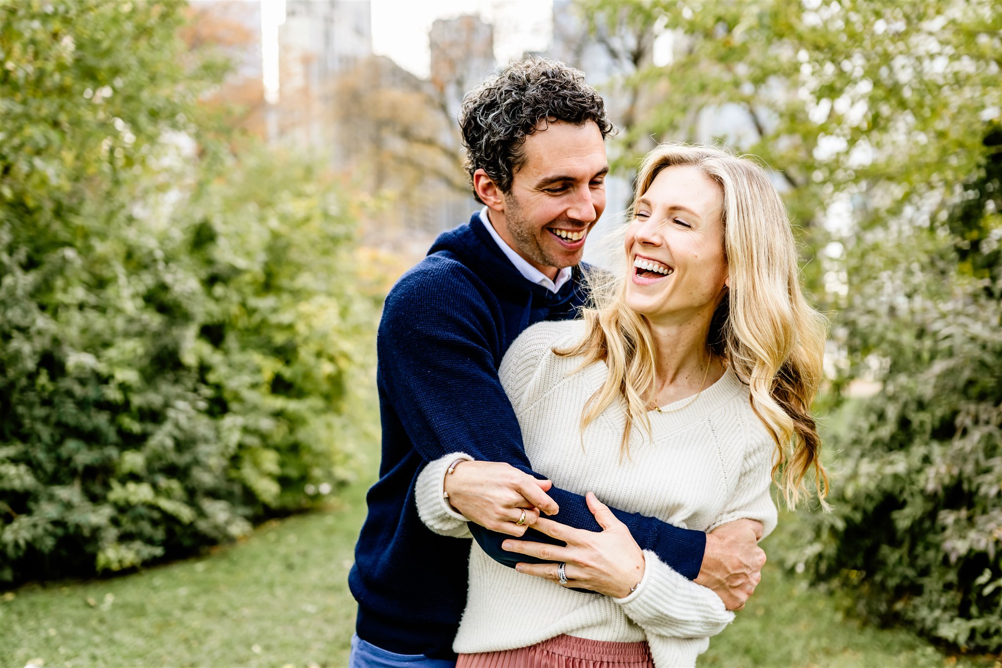 A couple in sweaters laugh and hug in a metro park before visiting Michelin Star Restaurants Chicago