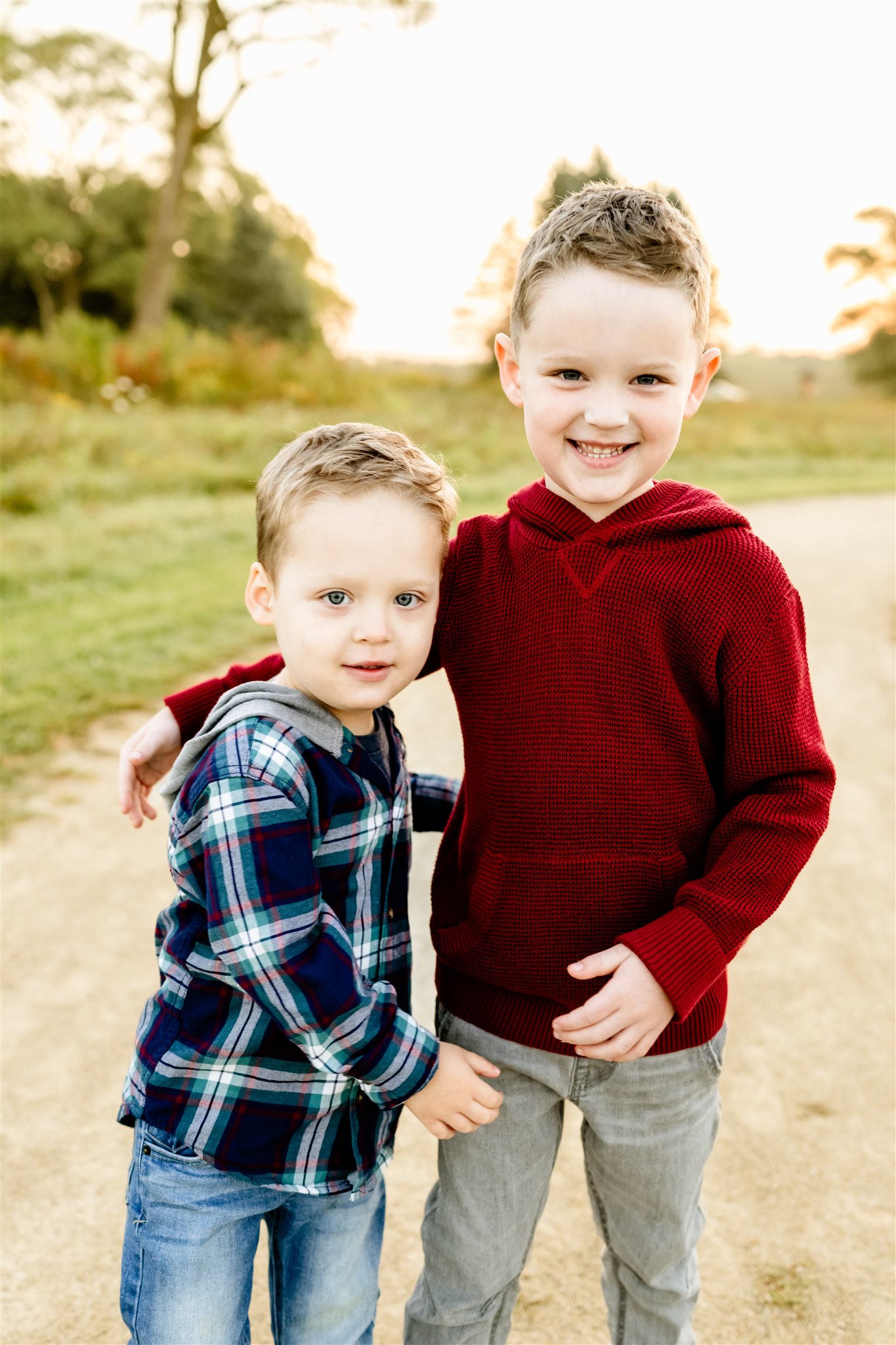 Two toddler brothers stand and hug each other in a park path at sunset after visiting Montessori Schools in Chicago Suburbs