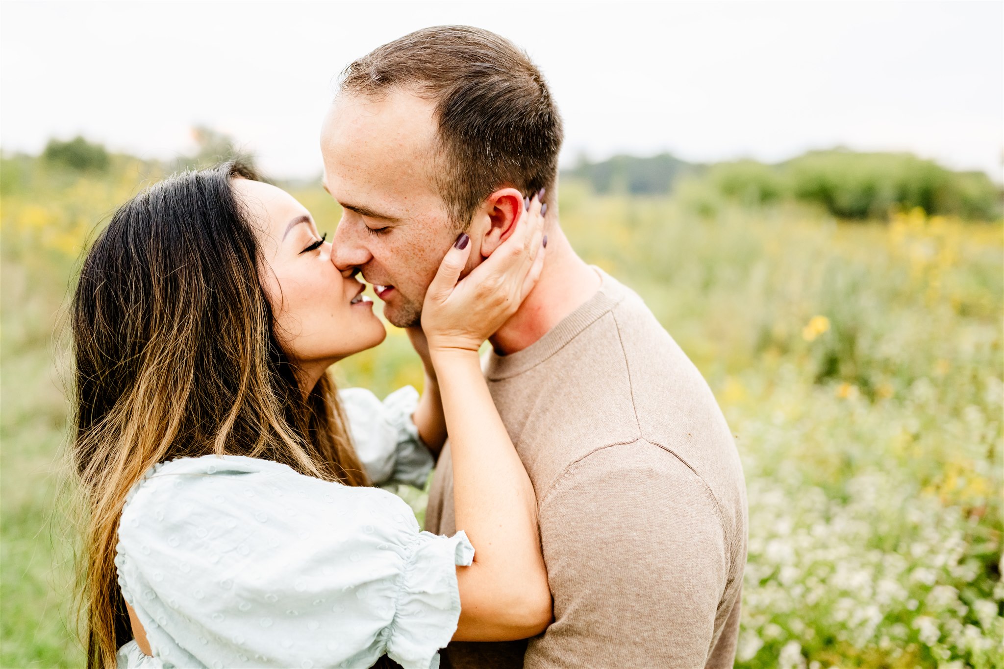 A couple lean in for a kiss while standing in a field of wildflowers during Naperville Activities For Couples