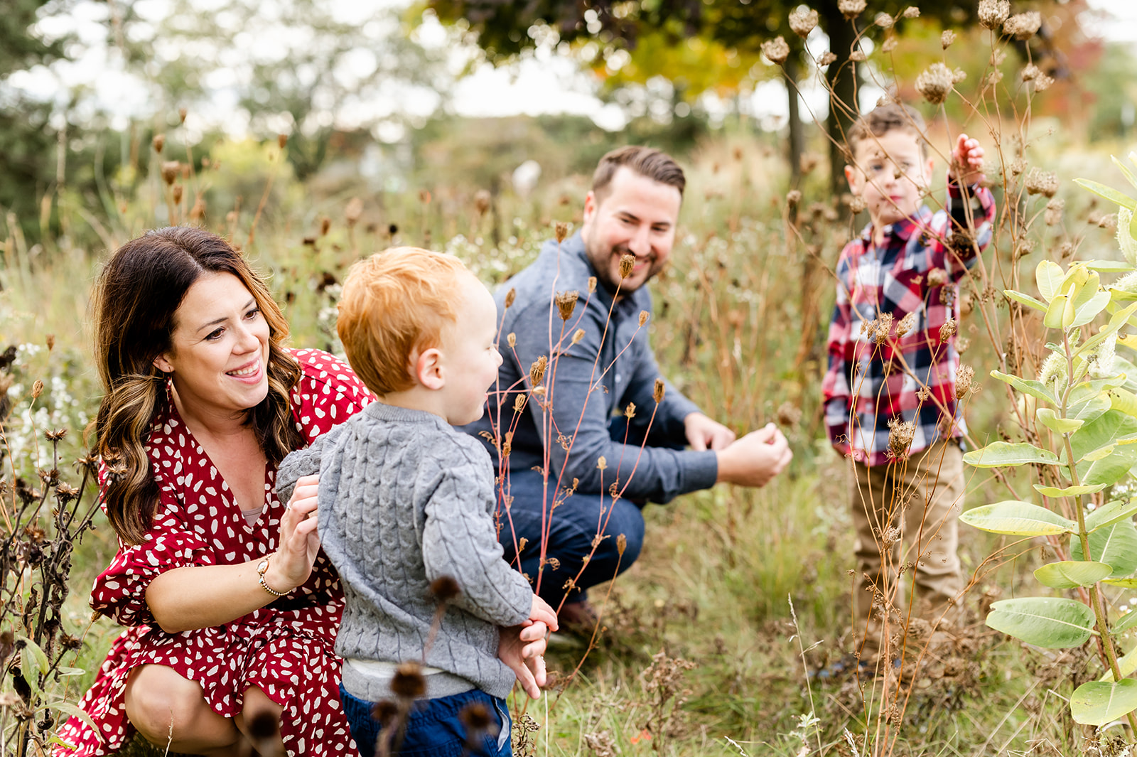 A mom and dad explore a field of tall grasses with their two toddler sons after some kids fitness classes in Chicago