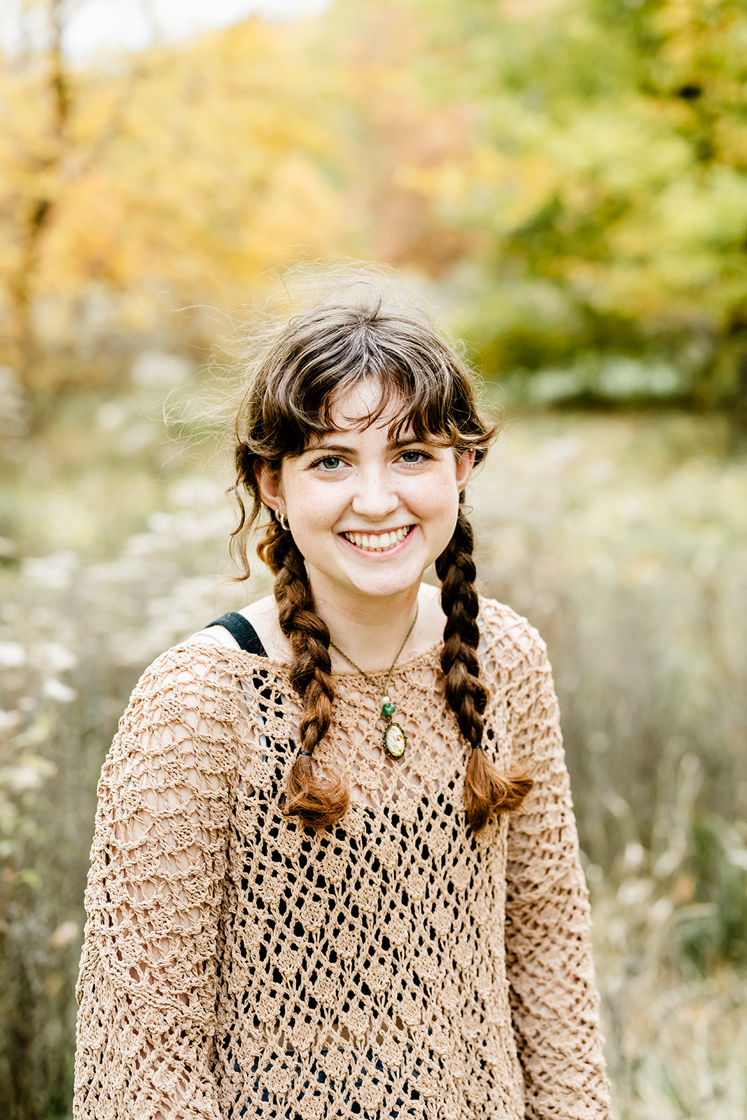 A smiling high school senior in a brown blouse walks in a park filled with wildflowers after using tutors in Chicago