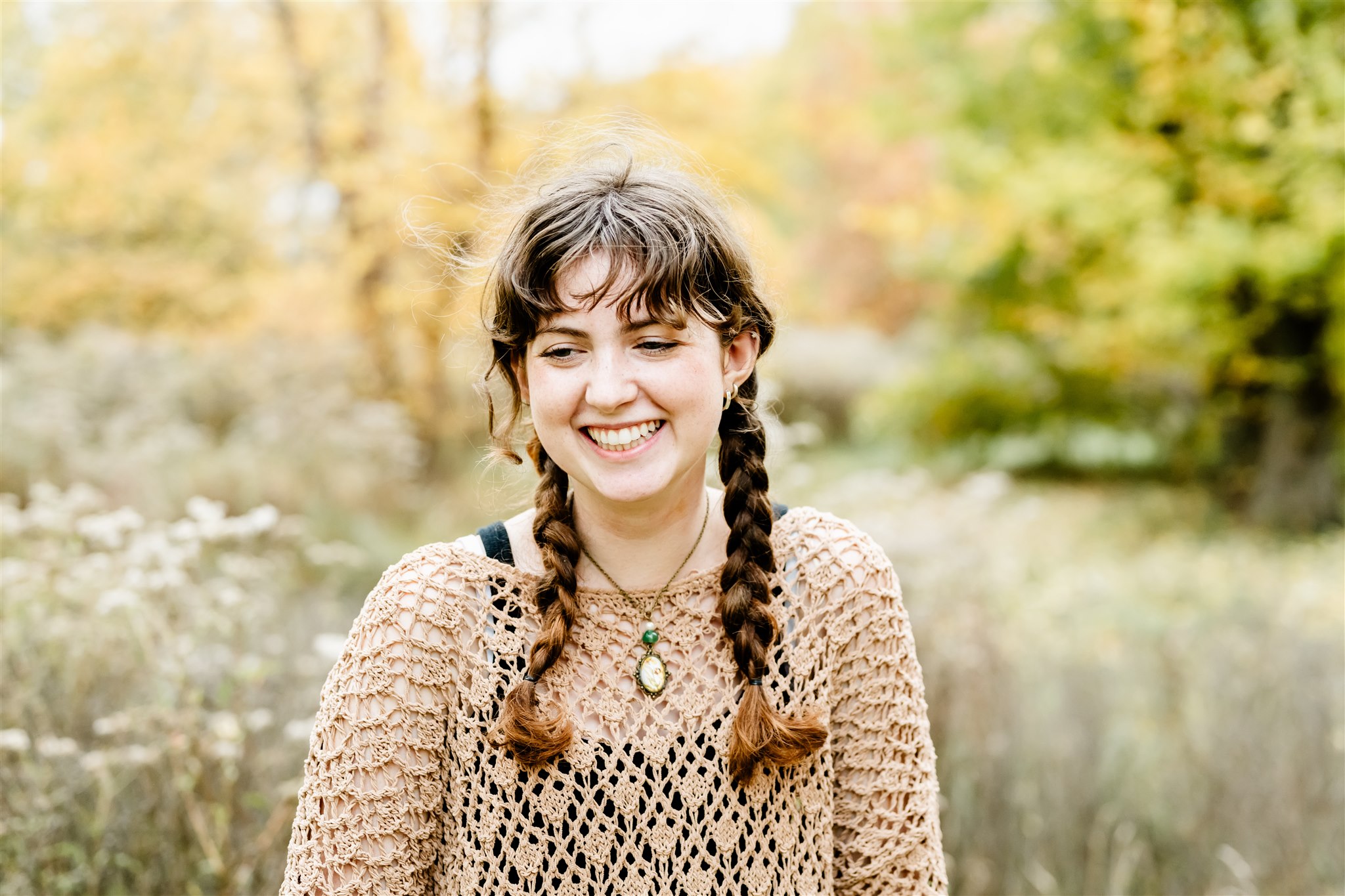 A high school senior giggles in a brown lace sweater with braids after visiting boutiques in Naperville