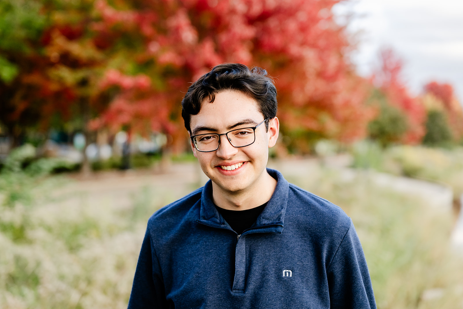 A smiling teenager in a black sweater in a park in fall after attending private high schools in Naperville