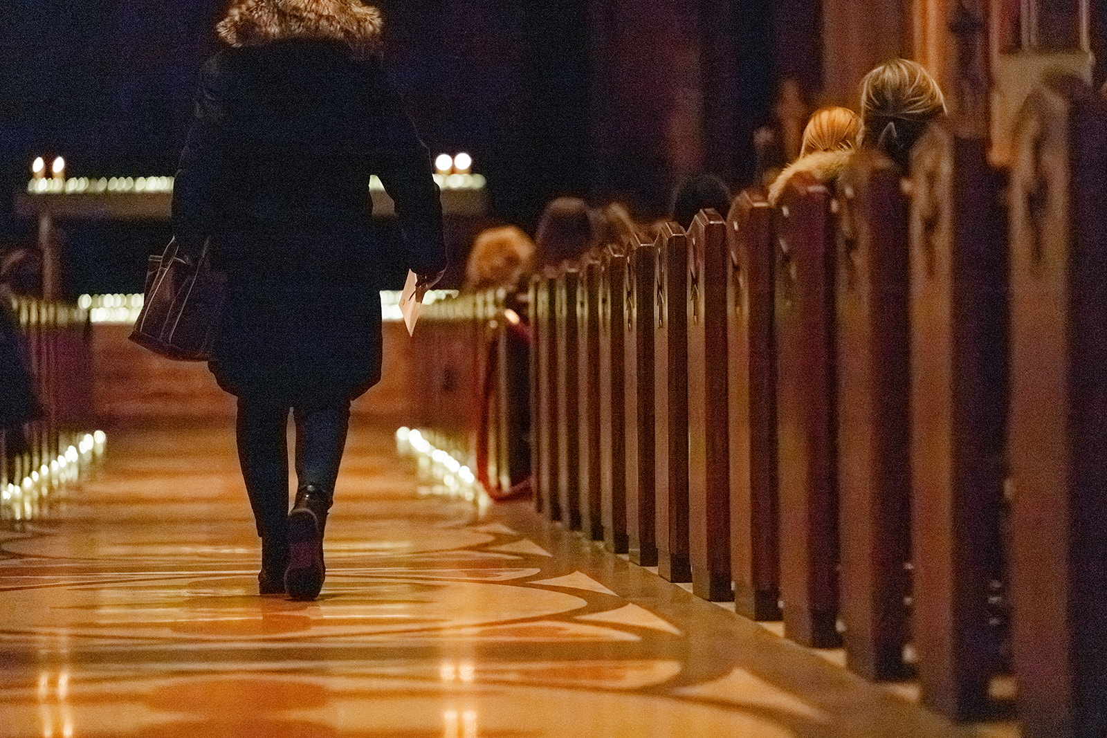 A woman walks down the church aisle in a sweater before a service