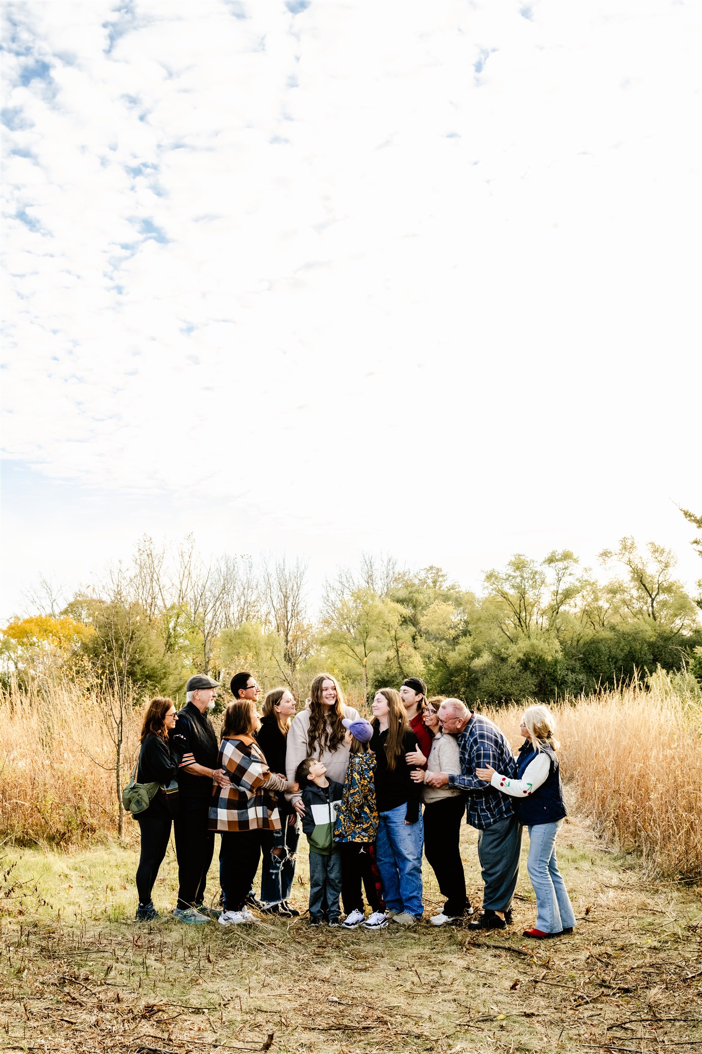A large family smiles big while in a park field with a survivor thanks to the Delnor Hospital Cancer Center