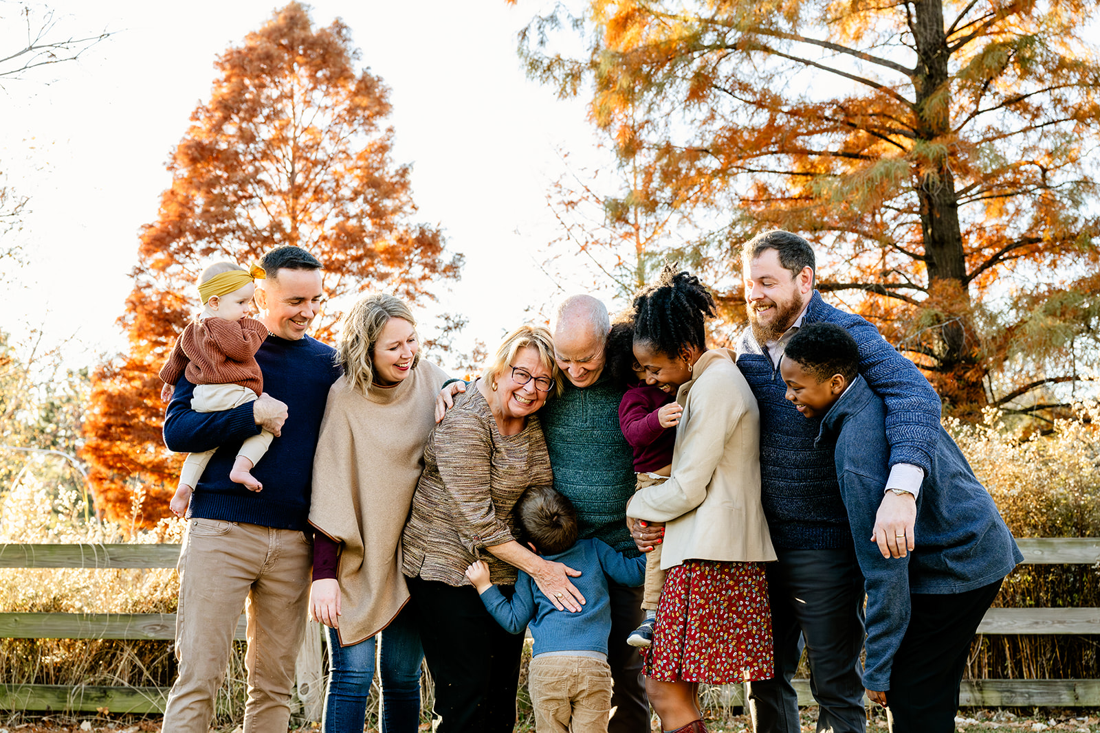 A large happy family hug and laugh while in a park in fall