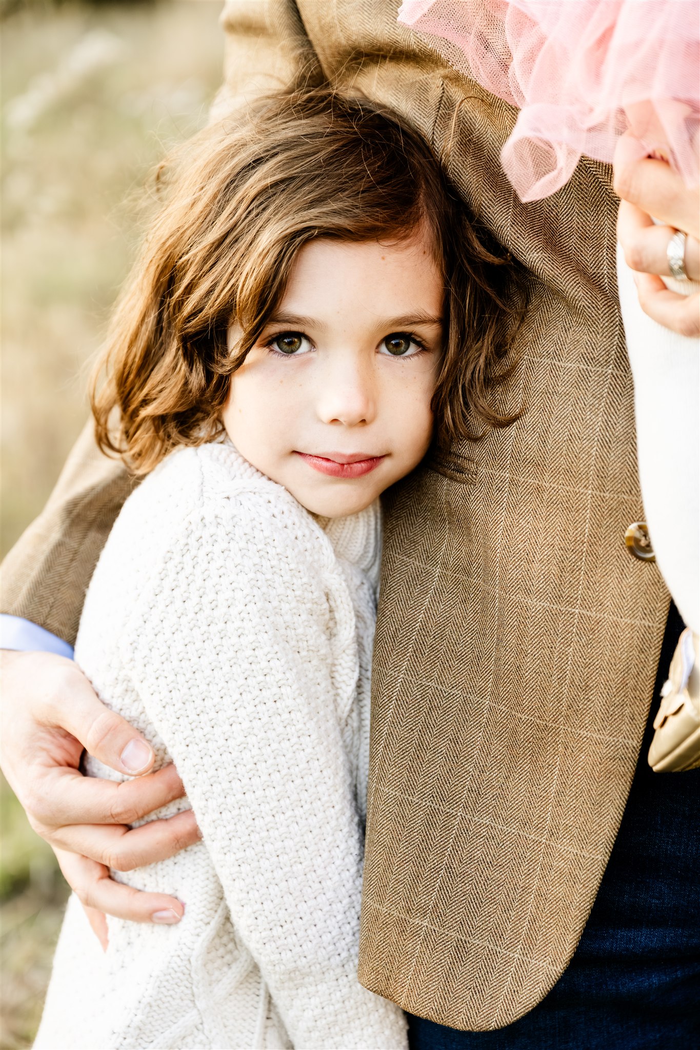 A toddler girl in a white knit sweater hugs and leans into mom while smiling after visiting pediatric chiropractors in Chicago