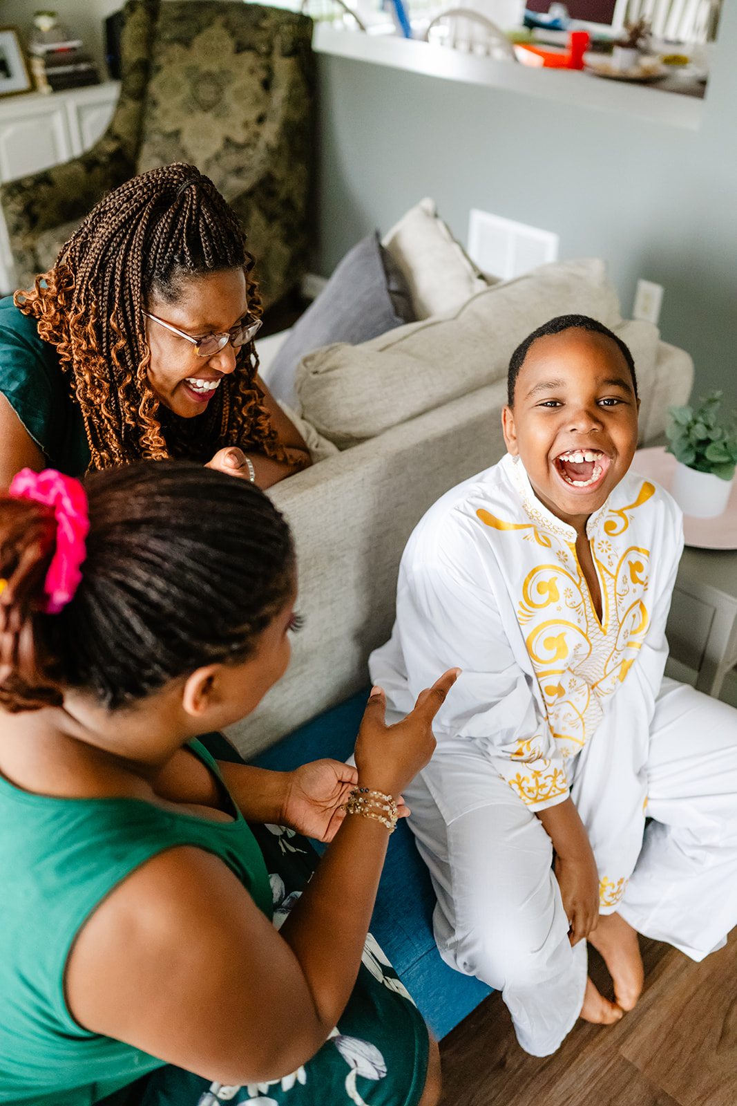 A happy family laughs while sitting around the living room in green and white after visiting a pediatric dentistry in North Shore