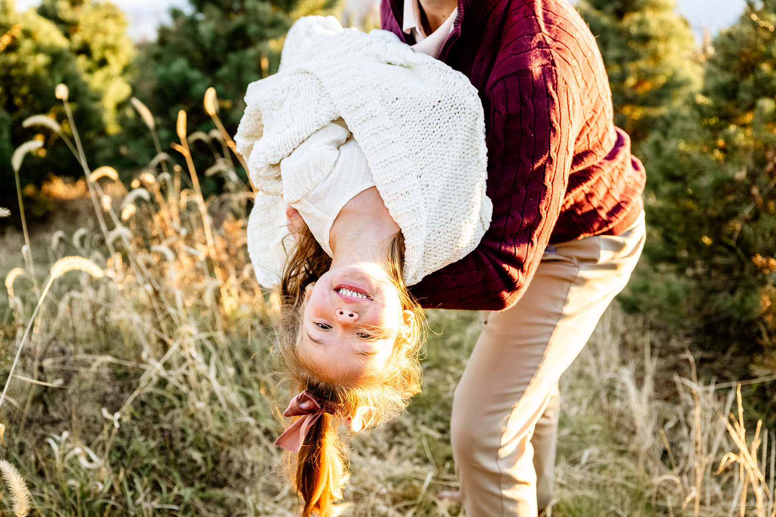 Dad flips his toddler daughter in a park trail at sunset in a white blanket after some speech therapy in Naperville