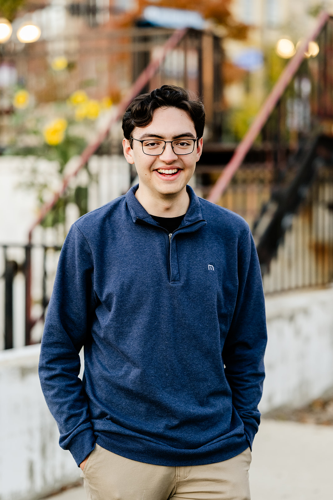 A happy high school senior in a blue sweater walks a sidewalk with a smile after finding great tutors in North Shore