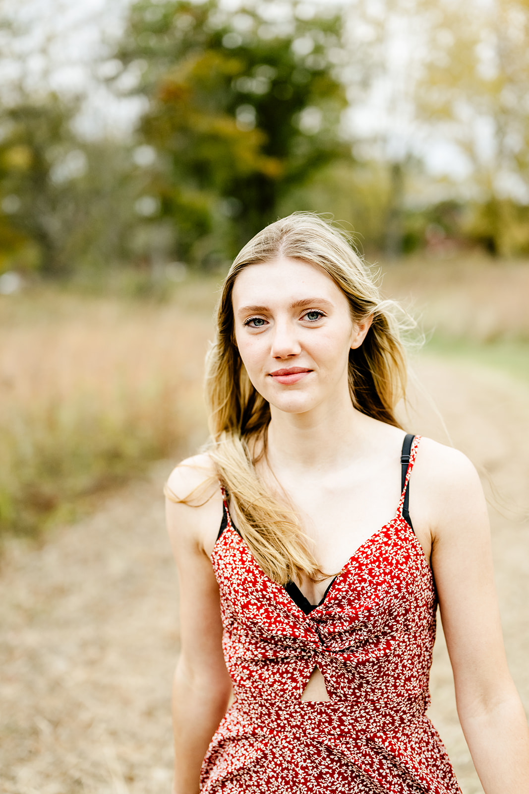 A high school senior in a red dress walks in a park trail at sunset after enjoying private school in North Shore Chicago