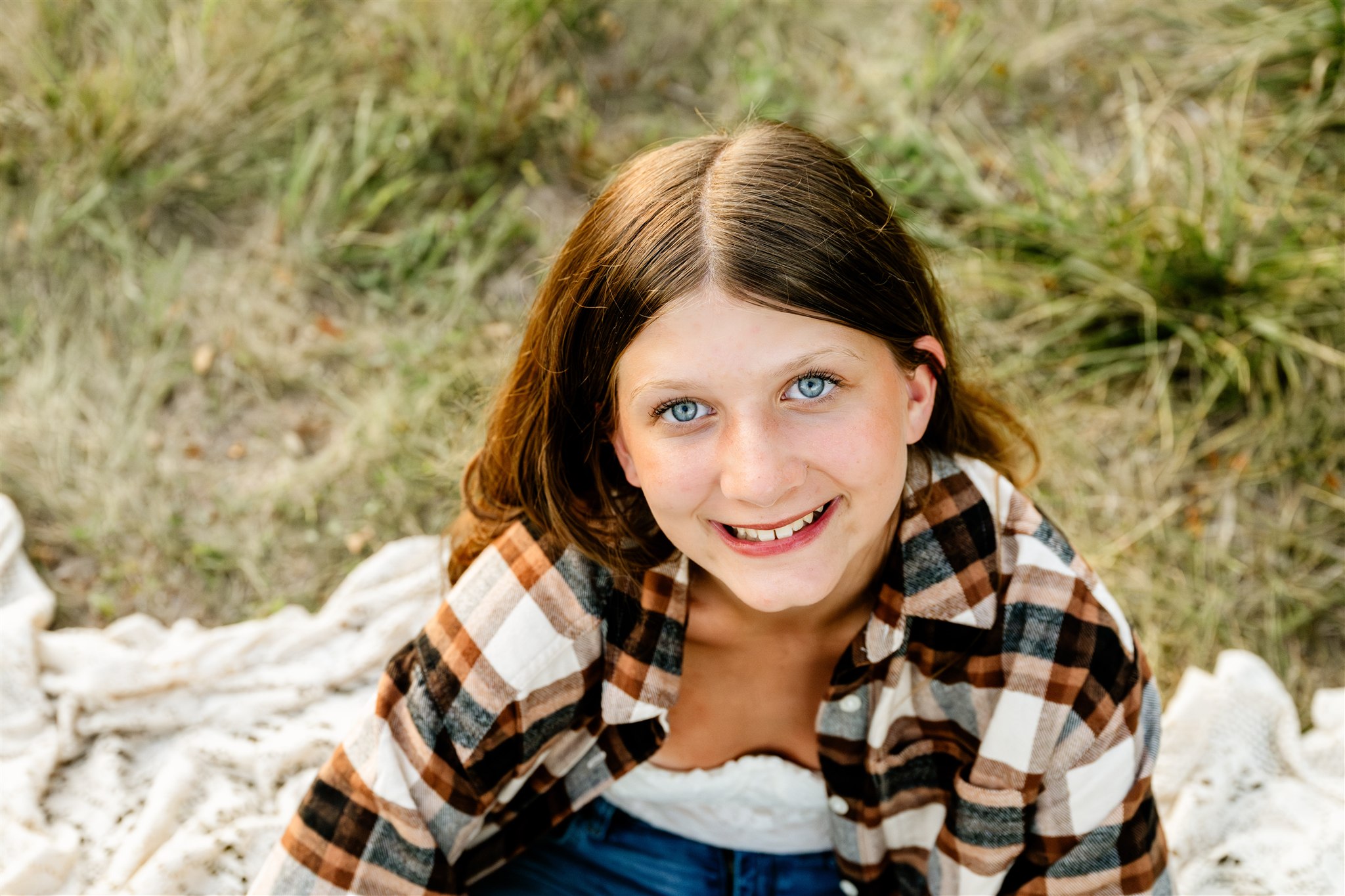 A closeup look at a smiling high school grad in brown plaid on a picnic blanket after visiting boutiques in North Shore