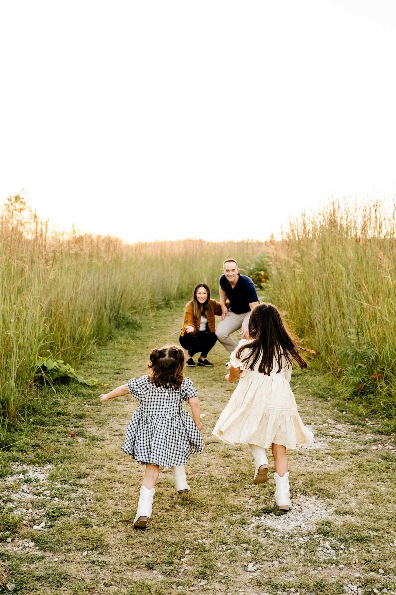 Toddler sisters in dresses run in a park trail through tall grass before visiting ice cream shops in Chicago