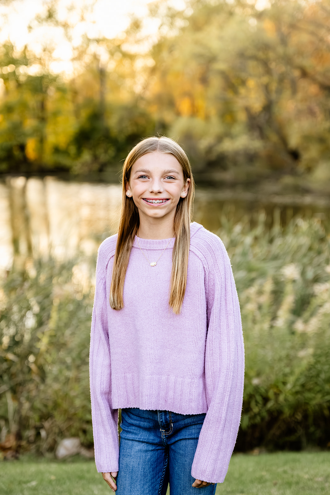 A young girl wearing jeans and a purple sweater smiles after visiting kid friendly trails in naperville.