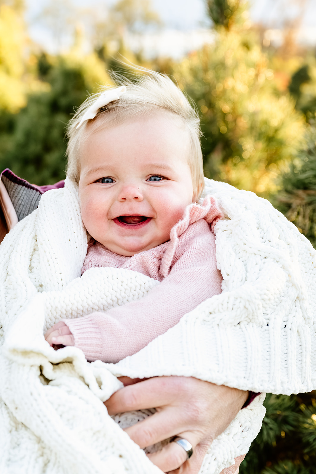A happy baby giggles in dad's arms while wrapped in a blanket after shopping for christening gowns in Naperville