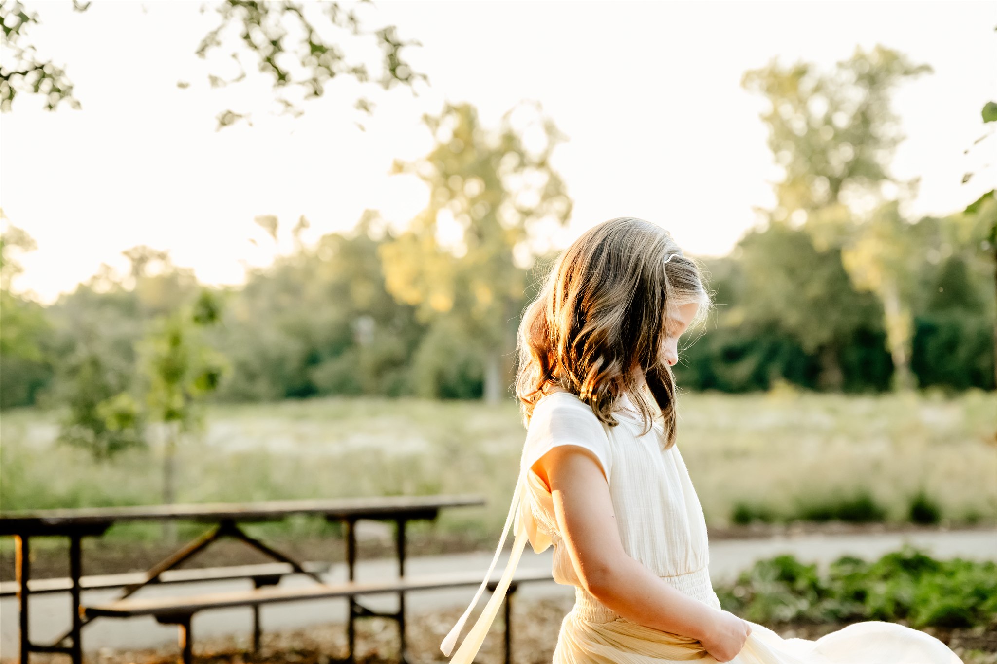 A young girl plays with her dress in a park at sunset after enjoying some dance classes in Naperville
