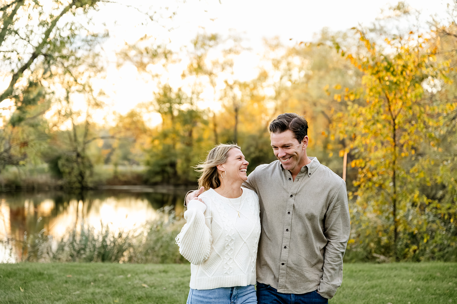 A happy man and wife walk arms around each other while laughing in a park by a pond before heading to romantic restaurants in North Shore