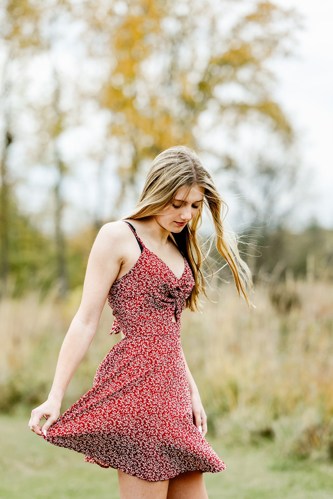 A high school senior in a red dress walks and plays in a trail at sunset after enjoying SAT prep in North Shore Chicago